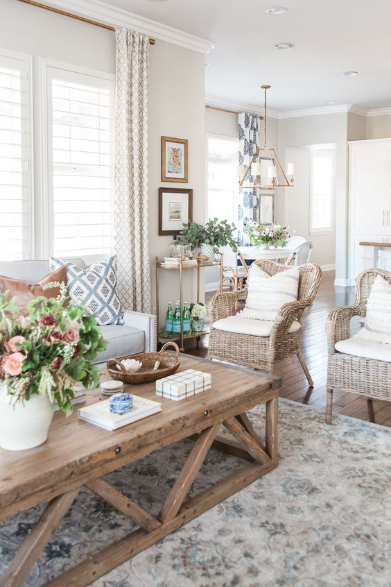 A-modern-country-living-room-in-neutrals-with-a-creamy-sofa-woven-chairs-a-low-coffee-table-printed-textiles-and-potted-plants