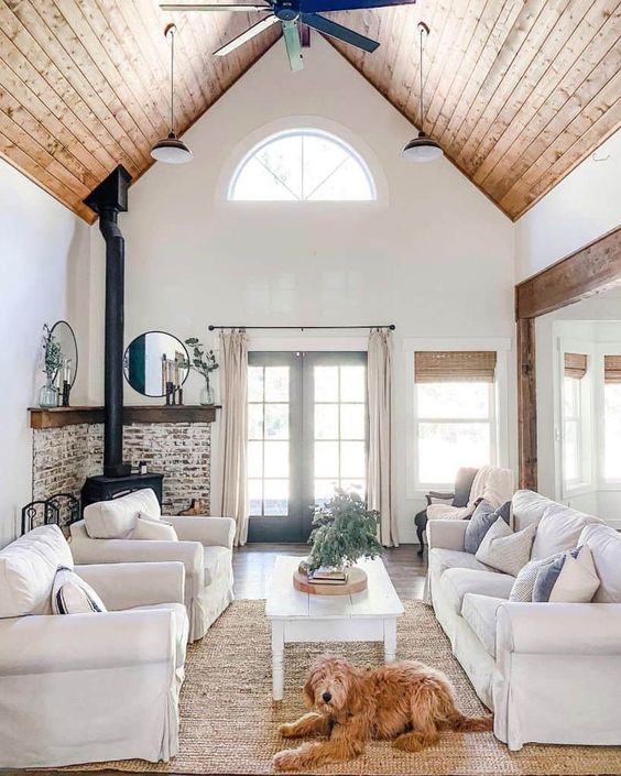 A-modern-country-living-room-with-a-hearth-neutral-furniture-a-highlit-slanted-ceiling-printed-and-neutral-textiles