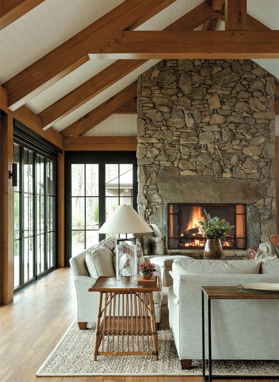 A-modern-farmhouse-living-room-with-a-gorgeous-fireplace-clad-with-stone-neutral-furniture-a-wooden-table-and-a-console-wooden-beams