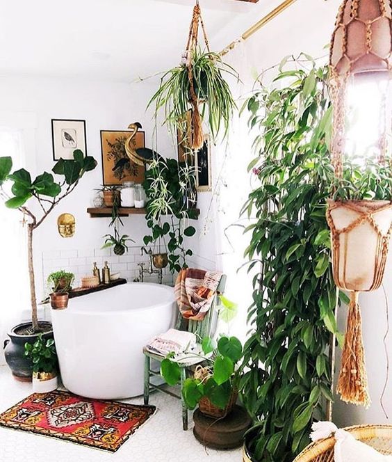 A-modern-meets-boho-bathroom-with-plants-in-hanging-pots-a-soak-tub-wooden-shelves-and-a-bold-boho-rug
