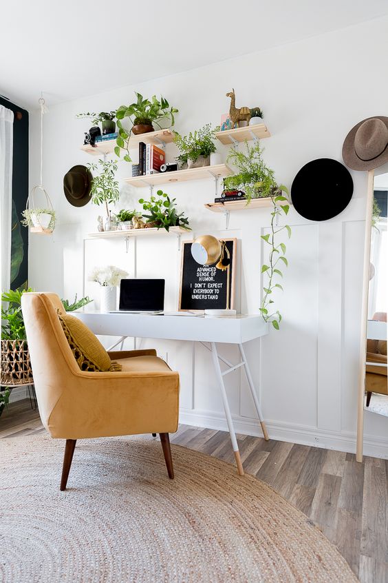 A-neutral-boho-home-office-with-a-tiny-desk-a-yellow-chair-and-open-shelves-with-climbing-plants-in-pots
