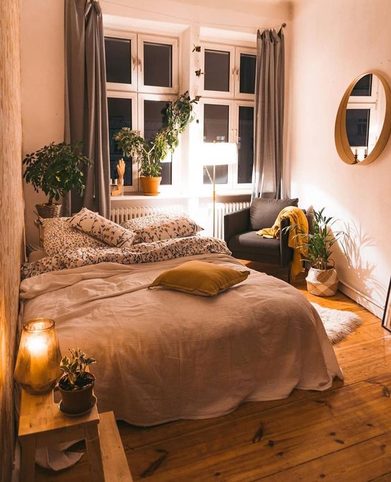 A-small-boho-bedroom-with-a-large-bed-potted-greenery-muted-color-textiles-and-a-mirror-on-the-wall