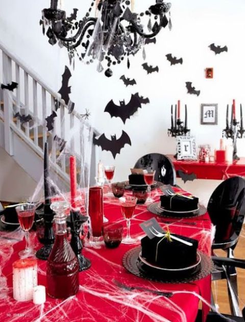 05-a-bold-black-and-red-tablescape-with-red-candles-a-red-tablecloth-bats-around-and-a-black-chandelier-with-spider-webs