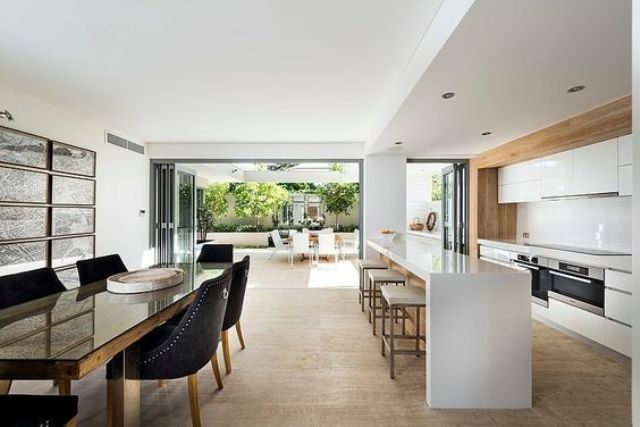 17-minimalist-white-kitchen-with-warm-woods-and-a-dining-space-with-black-chairs-for-a-contrast