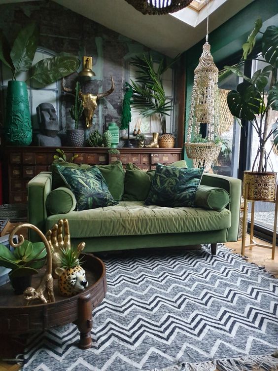 A-boho-living-room-with-a-black-brick-wall-and-green-walls-a-muted-grene-sofa-potted-plants-and-boho-accessories-and-details