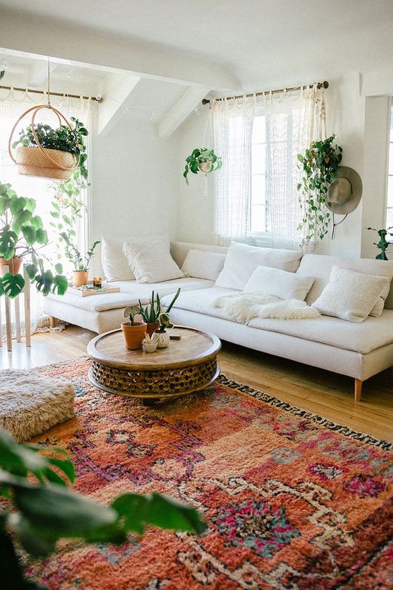 A-boho-living-room-with-a-neutral-sectional-plus-a-bold-rug-climbing-plants-and-a-fluffy-ottoman