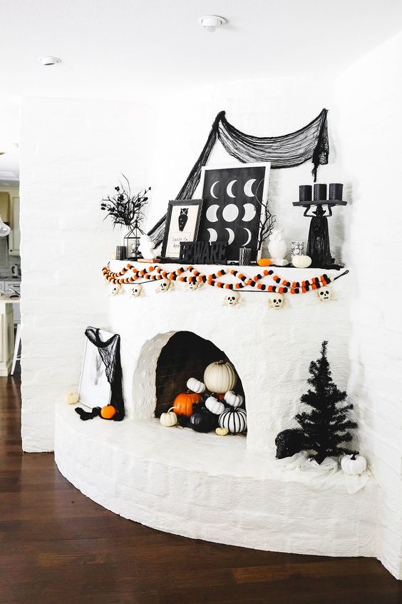 A-bold-halloween-mantel-with-colorful-garlands-letters-spiderweb-black-candles-branches-and-black-and-white-pumpkins