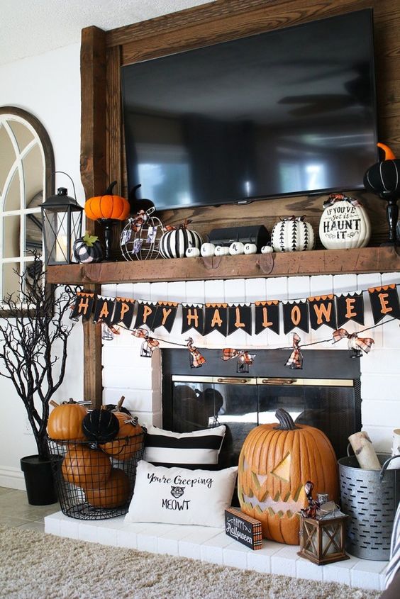 A-bold-and-chic-halloween-mantel-with-black-and-white-pumpkins-a-bright-bunting-and-orange-and-black-pumpkins