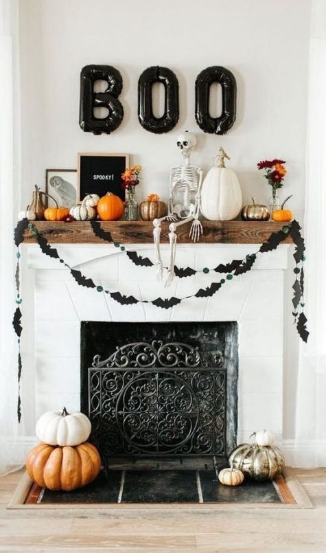 A-bright-halloween-mantel-with-a-bat-bunting-natural-and-painted-pumpkins-a-skeleton-black-balloon-letters-and-a-sign