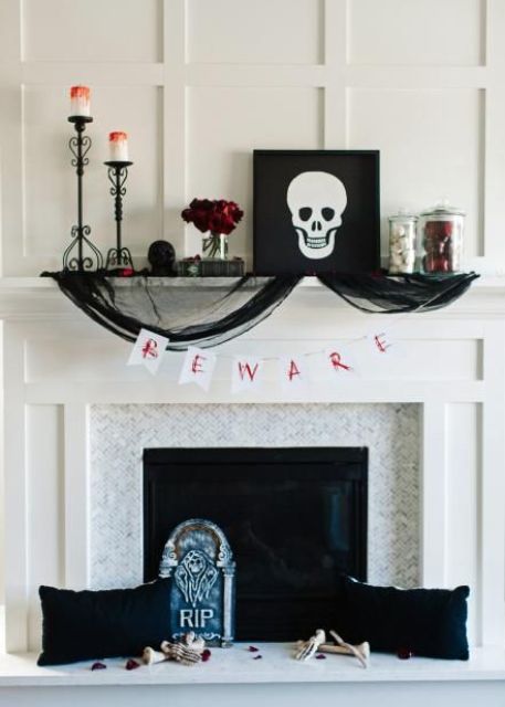 A-chic-halloween-mantel-with-bloody-candles-red-roses-a-skull-artwork-black-tulle-black-pillows-and-skeleton-hands