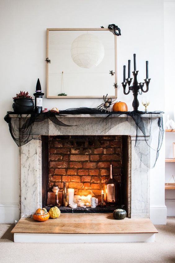 A-chic-halloween-mantel-with-candles-bottles-a-witch-hat-black-tulle-natural-pumpkins-and-blooms-in-a-cauldron