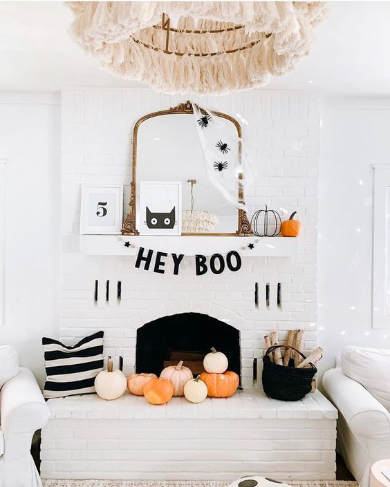 A-chic-halloween-mantel-with-spiderweb-and-spiders-on-the-mirror-pumpkins-a-black-garland-and-pumpkins-in-the-fireplace