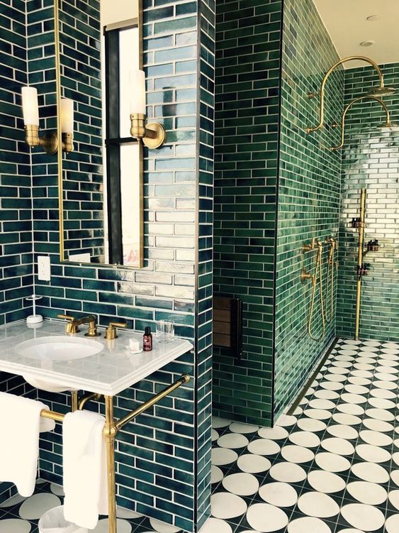 A-chic-art-deco-bathroom-with-dark-green-tiles-gold-and-brass-touches-a-stone-vanity-and-black-and-white-mosaic-tiles