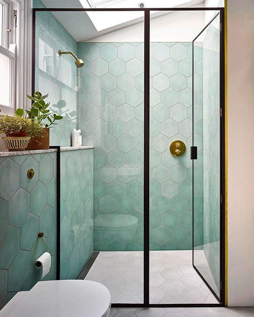 A-chic-bathroom-with-pale-green-hex-tiles-a-skylight-black-framing-is-a-catchy-and-contemporary-space