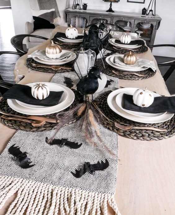 A-chic-black-and-white-halloween-tablescape-with-black-crows-bats-napkins-painted-pumpkins-woven-placemats-and-wheat