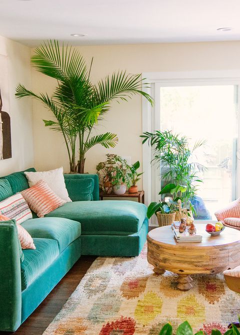 A-colorful-tropical-living-room-with-an-emerald-sofa-a-colorful-boho-rug-potted-plants-and-a-round-wooden-table