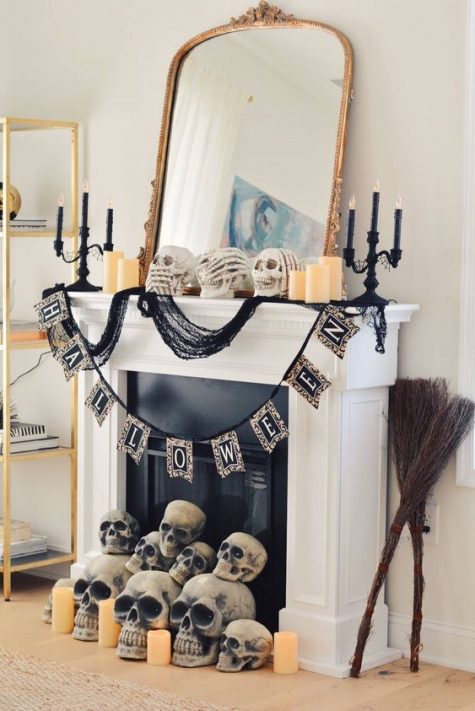A-glam-halloween-mantel-with-a-large-mirror-black-candleholders-a-bunting-and-lots-of-skulls