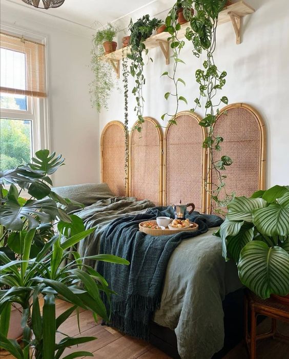 A-jungle-themed-bedroom-with-a-rattan-screen-green-bedding-statement-potted-plants-and-climbing-ones