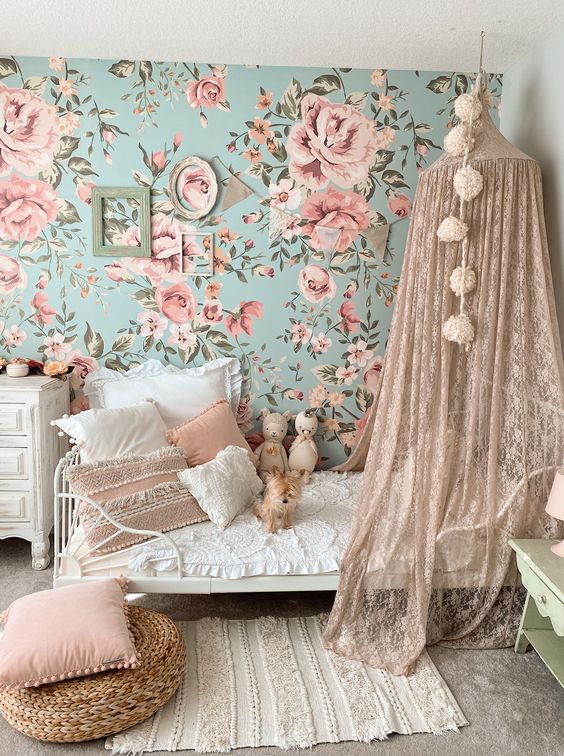 A-lovely-and-delicate-girls-bedroom-with-a-blue-and-pink-floral-wall-a-bed-with-a-blush-lace-canopy-pink-pillows-and-frames