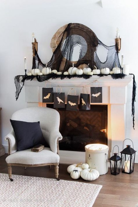 A-monochromatic-halloween-mantel-with-black-tulle-feathers-white-pumpkins-and-candles