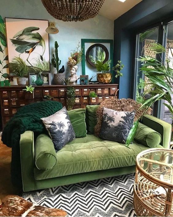 A-moody-tropical-living-space-with-blue-walls-a-vintage-sideboard-a-green-sofa-a-printed-rug-and-bold-artworks