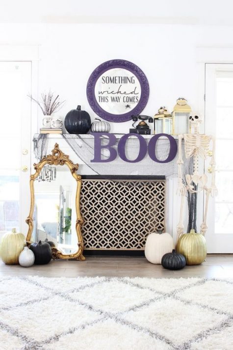 A-refined-halloween-mantel-with-a-purple-sign-and-letters-a-skeleton-pumpkins-lanterns-and-a-mirror