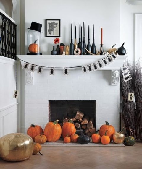 A-refined-halloween-mantel-with-black-and-orange-candles-a-bug-garland-a-top-hat-various-pumpkins-and-black-bottles