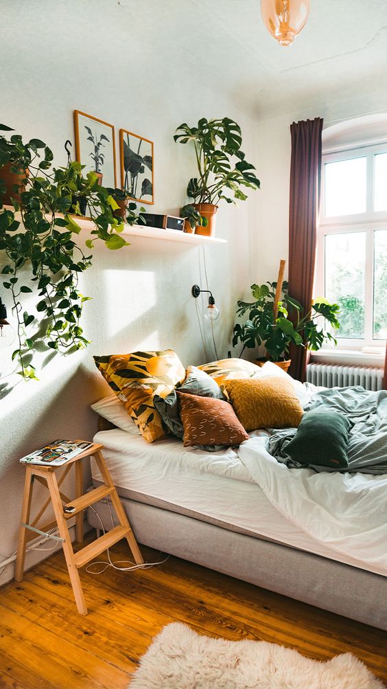 A-relaxed-boho-bedroom-in-neutrals-with-colorful-textiles-potted-greenery-and-climbing-plants-is-very-cozy
