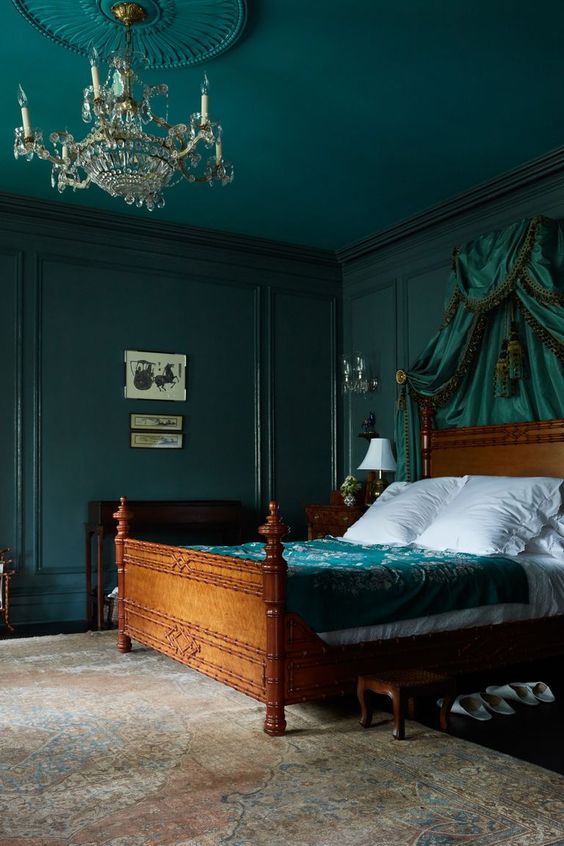 A-sophisticated-bedroom-with-dark-green-walls-and-a-ceiling-a-green-canopy-and-bedding-is-moody-and-chic