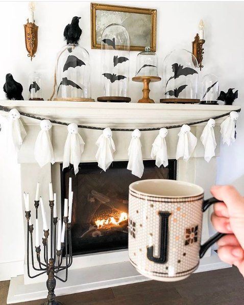 A-stylish-halloween-mantel-with-a-ghost-garland-bats-in-cloches-and-blackbirds-is-an-elegant-piece