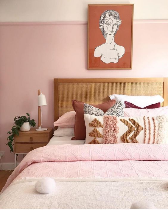 A-stylish-modern-bedroom-with-light-pink-walls-pink-neutral-and-burgundy-bedding-wooden-furniture-and-a-statement-artwork