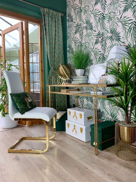 A-tropical-home-office-with-a-leaf-accent-wall-printed-green-curtains-lots-of-plants-and-boxes-and-much-gold-for-a-glam-feel
