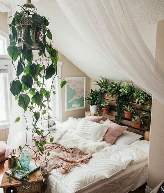 An-attic-boho-bedroom-in-neutrals-with-a-pallet-vertical-garden-a-climbing-plant-in-a-cage-and-a-cozy-bed