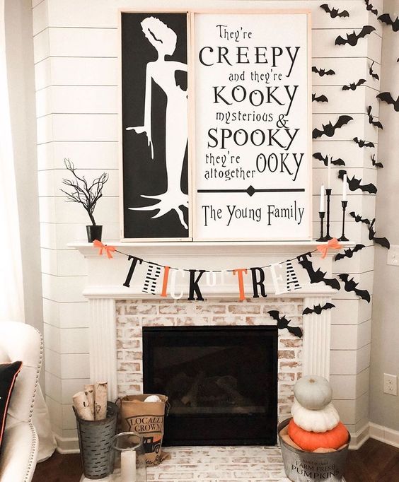 An-elegant-contrasting-fireplace-with-two-monochromatic-signs-bats-a-bright-bunting-and-stacked-pumpkins
