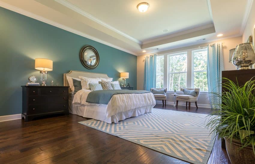 Beautiful-bedroom-with-blue-green-painted-accent-wall-white-room-paint-window-sitting-area-and-wood-flooring