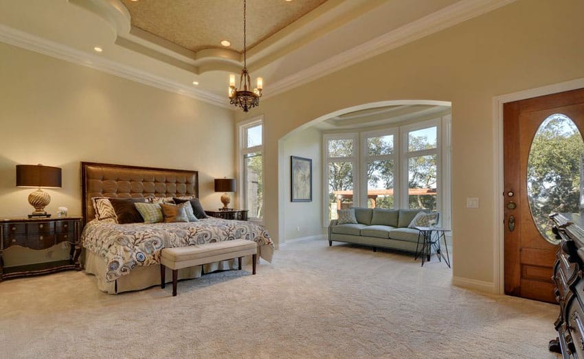 Beautifully-decorated-tan-bedroom-with-sitting-area-and-high-ceiling