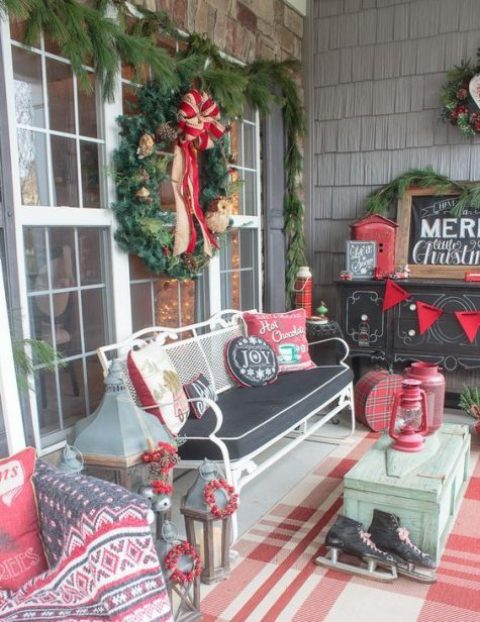 16-a-vintage-christmas-porch-in-red-white-and-black-with-comfy-furniture-and-colorful-pillows-skates-an-evergreen-wreath-and-evergreens-all-around
