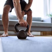 Closeup of man grabing kettlebell during home workout exercises
