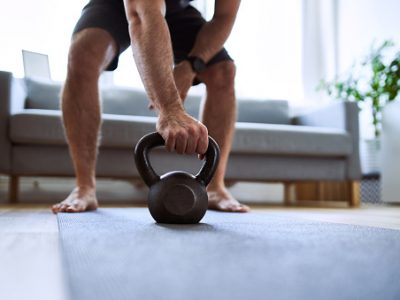 Closeup of man grabing kettlebell during home workout exercises