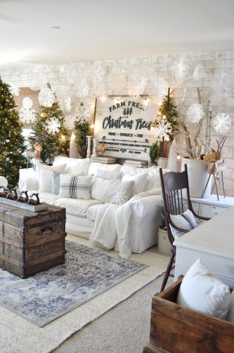 26-clusters-of-christmas-trees-with-lights-lots-of-paper-snowflakes-lights-signs-branches-and-a-white-sofa-with-pillows-for-a-winter-wonderland-feel