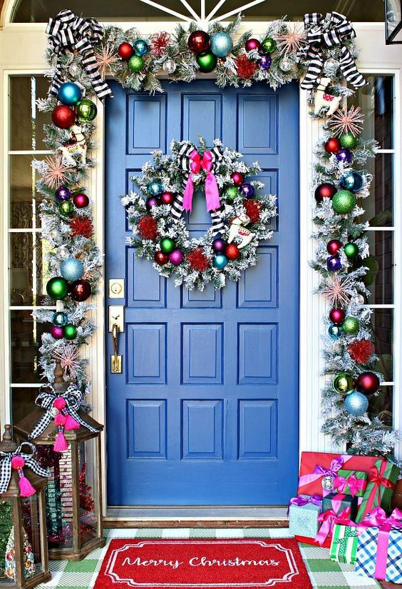 Super-bright-christmas-front-door-decor-with-a-silver-garland-with-colorful-ornaments-striped-bows-and-a-matching-wreath-plus-colorfil-gift-boxes