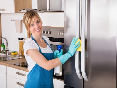 Smiling woman cleaning refrigerator