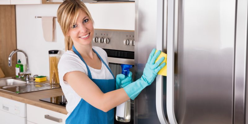 Smiling woman cleaning refrigerator
