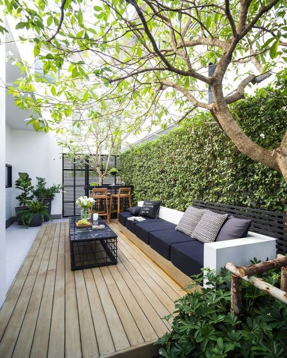 A-modern-welcoming-backyard-with-a-deck-s-amll-bar-space-a-large-sofa-and-a-black-coffee-table-plus-a-living-wall