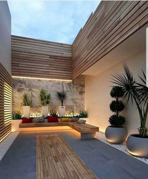 A-simple-minimalist-patio-with-a-corner-bench-a-deck-colorful-pillows-and-potted-plants