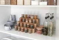 Food and spices in clear jars on white shelves