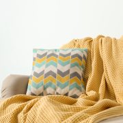 Cozy sofa with pillow and plaid near light wall. idea for living