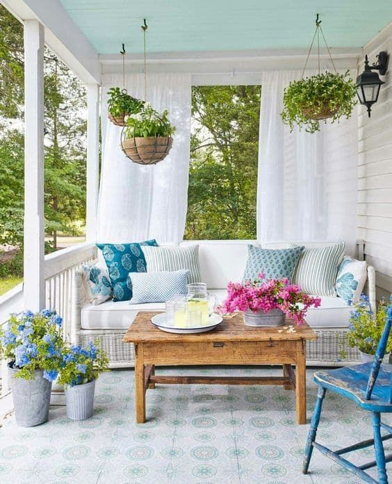 A-colorful-spring-porch-with-potted-greenery-and-blooms-printed-pillows-and-vintage-furniture
