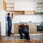 Two senior men, manual workers assembling kitchen furniture in new apartment
