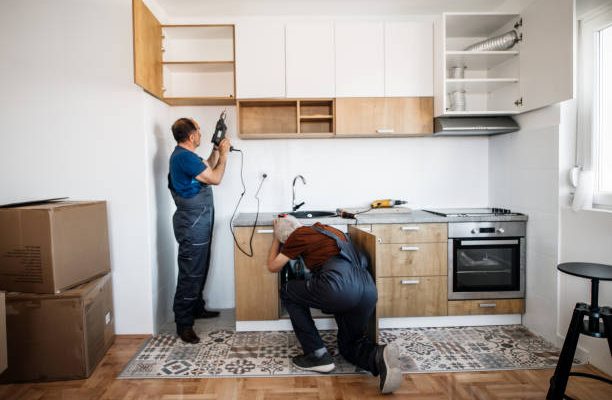 Two senior men, manual workers assembling kitchen furniture in new apartment